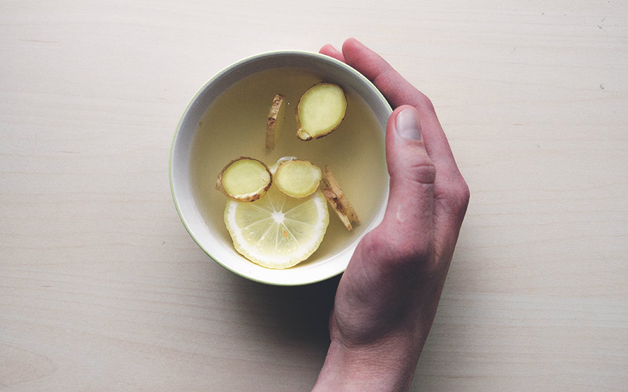 Bild på en hand som håller en kopp med ingefära-te